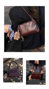 Detail of dark red leather crossbody bag with a brown plush bear charm and metal logo