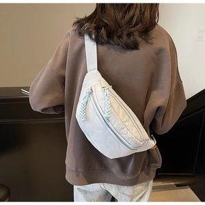 Detailansicht der hellblauen gesteppten Brusttasche mit verstellbarem Riemen am Model