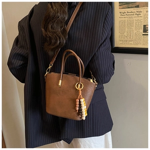 Retro brown leather bucket bag with wooden bead charm styled on a striped blazer