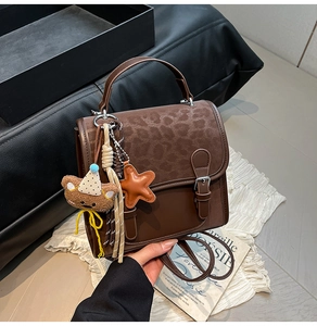 Close-up of brown leopard print handbag featuring bear charm and tassel detail