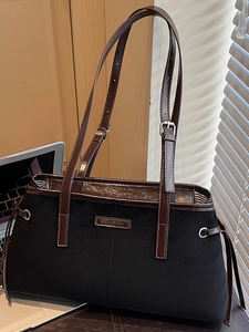 Chic black tote bag with brown leather straps and silver hardware in minimalist style