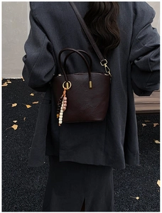 Detail of vintage brown leather bucket bag with bohemian beads in an autumn street setting