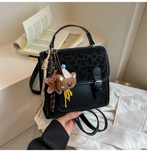 Detail of black faux leather backpack with leopard print flap and plush bear charm