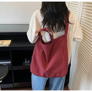 Gros plan du sac cabas en toile à carreaux rouges montrant la texture et les bandoulières