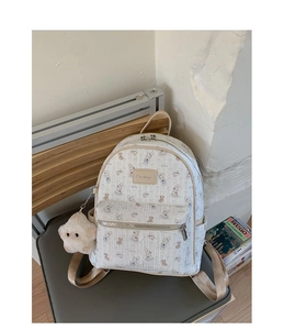 Détail d'un sac à dos imprimé beige avec un charmant pendentif en forme d'étoile sur chaise