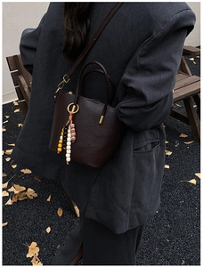 Fashionable dark brown leather shoulder bag with vintage beaded charm in autumn setting