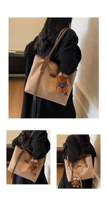 Detail of khaki suede tote bag with brown straps and cute teddy bear charm pendant