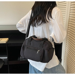 Detail of black multi-pocket crossbody bag featuring contrasting brown top handles