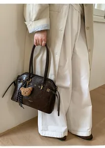 Détail d'un sac cabas en cuir ciré vintage marron foncé avec un pendentif d'ours