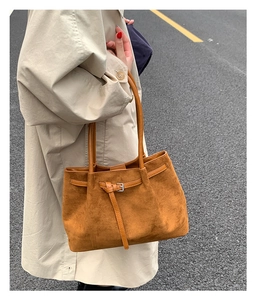 Detail view of brown faux suede Boston bag with silver buckle on a stylish beige trench coat