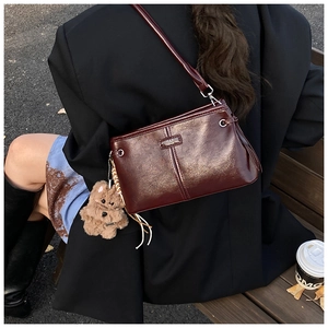 Chic burgundy patent leather crossbody bag with logo detail and cute bear charm pendant