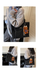 Detail view of large black canvas tote bag featuring a cute brown plush bear charm