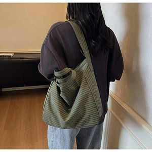 Détail de la texture du sac cabas en toile à carreaux vert foncé et de la grande bandoulière