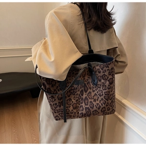 Detailed close-up of large leopard print tote bag with black leather shoulder strap and trim