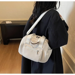 Detail of a white waterproof nylon crossbody bag with multiple zipper pockets and wide straps