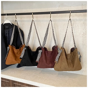 Detail of four suede hobo bags with unique black and white striped woven straps