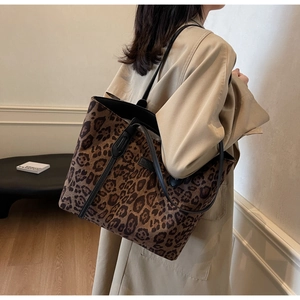 Lifestyle view of a large leopard print tote bag with black handles on a model's shoulder