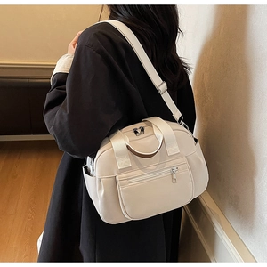 Detail showing beige multi-pocket crossbody bag with wide strap and silver hardware