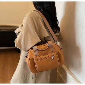 Detail view of caramel nylon shoulder bag with wide strap and multiple zipper pockets