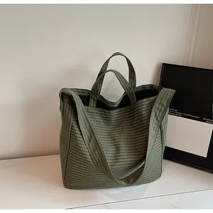 Détail du sac cabas à carreaux vert foncé avec texture en toile épaisse et bandoulières solides