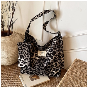Detailed macro view of leopard print tote bag with small matching pouch on woven mat