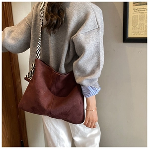 Detail view of large burgundy suede tote bag with a striped silk scarf on the shoulder strap