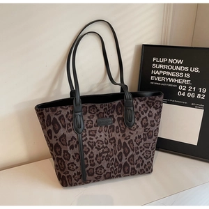 Detailed close-up of a leopard print tote bag with black straps and brand logo plate