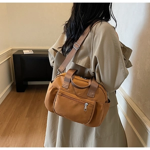 Detailed shot of multi-pocket nylon shoulder bag with adjustable strap and silver zippers