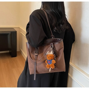 Detail of vintage brown suede tote bag with leather trim and cute teddy bear pendant