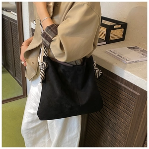 Detail of vintage tote bag with black and white striped woven strap on model's shoulder