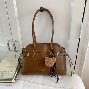 Détail du sac cabas en cuir ciré vintage avec logo doré et charm d'ours en peluche