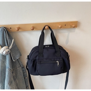 Detail of a black nylon shoulder bag with silver hardware on a wooden hanger