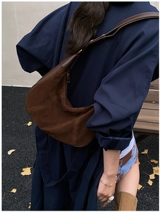 Détail du sac hobo en daim marron foncé avec coutures contrastées et bandoulière en cuir