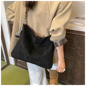 Detail of matte black tote bag with stylish black and white striped bow shoulder strap