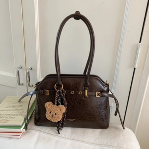Vue détaillée du sac cabas en cuir marron foncé avec œillets dorés et charme d'ours