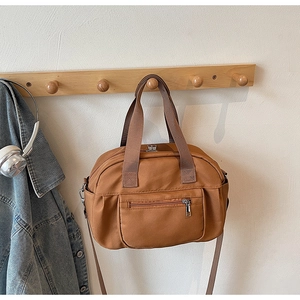 Detail showing the brown nylon bag's metal zipper pocket and multi-pocket design
