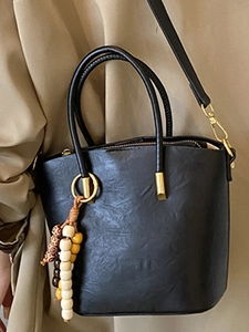 Retro black leather bucket bag with boho bead charm and shoulder strap on model
