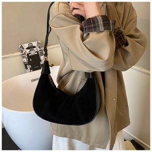 Vue détaillée du sac demi-lune en daim noir avec fermeture éclair dorée et trench beige