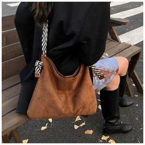 Brown suede crescent tote bag with a zebra pattern wide strap in an outdoor setting