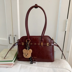 Détail du sac cabas en cuir ciré bordeaux avec œillets dorés et charmant ours en peluche