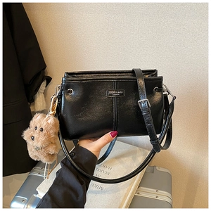 Close-up of black retro shoulder bag with MIQIER label and brown plush bear charm