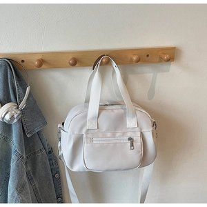 Nylon boston bag with double handles and adjustable strap hanging on wooden wall hook