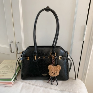 Détail de la texture du cabas en cuir ciré noir avec charm ours et finitions dorées