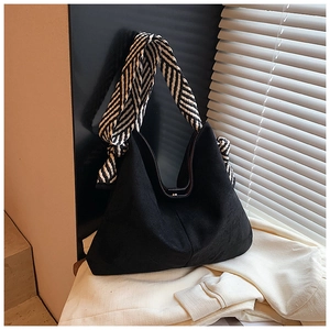 Detail of a black hobo bag with a black and white twill scarf wrapped on the wide strap