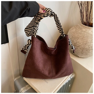 Detail of dark brown suede tote featuring a chic black and white woven handle and knots