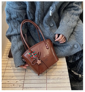 Close-up of vintage brown leather bag with star pendant, colorful beads and bow detail