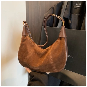 Détail du sac hobo en daim marron foncé avec anneaux dorés vintage et surpiqûres