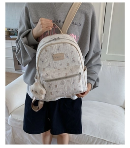 Détail du sac à dos blanc avec motif d'ours mignon, pendentif peluche et texture tissée