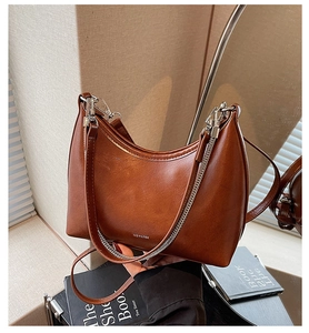 Detail of glossy brown textured leather bag with silver chain and NO FILTER logo