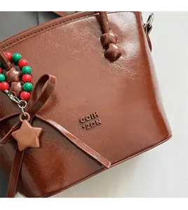 Detail of brown oil wax leather handbag with leather bow and star charm decoration